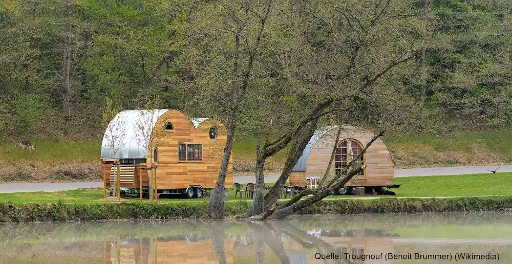Zwei Tiny Houses aus Holz an einem Seeufer.
